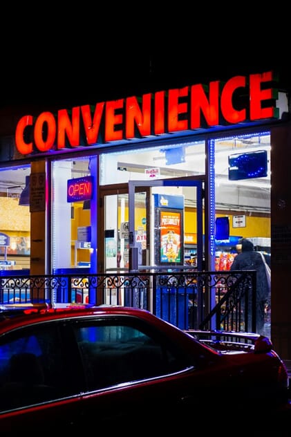 An image of the lit up outdoor channel letters for a convenient store at night.